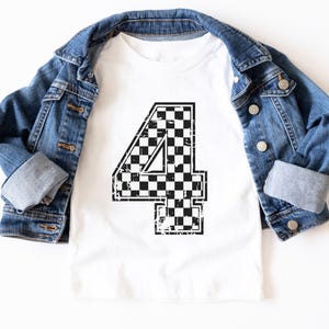 Pu&ograve; includere: T-shirt bianco con un grande numero 4 a scacchi in bianco e nero. Una giacca di jeans blu &egrave; appoggiata sulla maglietta. Il design ha un aspetto vintage.