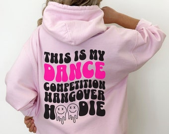 以下が含まれることがあります： 「THIS IS MY DANCE COMPETITION HANGOVER HOODIE」の文字が黒とホットピンクでプリントされた、薄いピンク色のパーカー。 ドローストリングフードとカンガルーポケットが付いています。 デザインには、溶けたスマイリーフェイスが2つ含まれています。