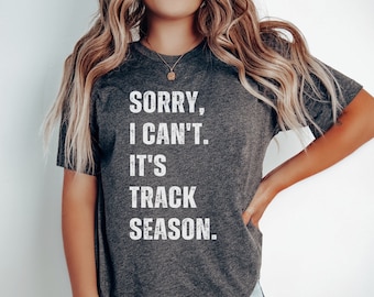 May include: A dark gray t-shirt with the text "Sorry, I can't. It's track season." printed in white.