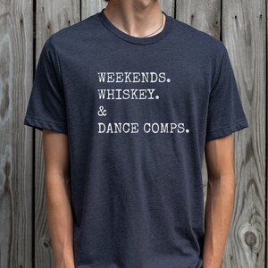 May include: A dark blue t-shirt with white text that reads "Weekends. Whiskey. & Dance Comps."