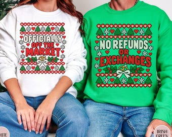 Könnte beinhalten: Ein weißes Sweatshirt mit dem Text "OFFICIALLY OFF THE MARKET" und ein grünes Sweatshirt mit dem Text "NO REFUNDS OR EXCHANGES". Beide zeigen ein rot-grünes Weihnachtsmuster mit Herzen, Tannenbäumen und Ringen.