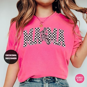 Peut inclure: T-shirt rose avec un motif &agrave; carreaux noir et blanc qui &eacute;pelle "MAMA" avec un graphisme de pilote de motocross au centre.