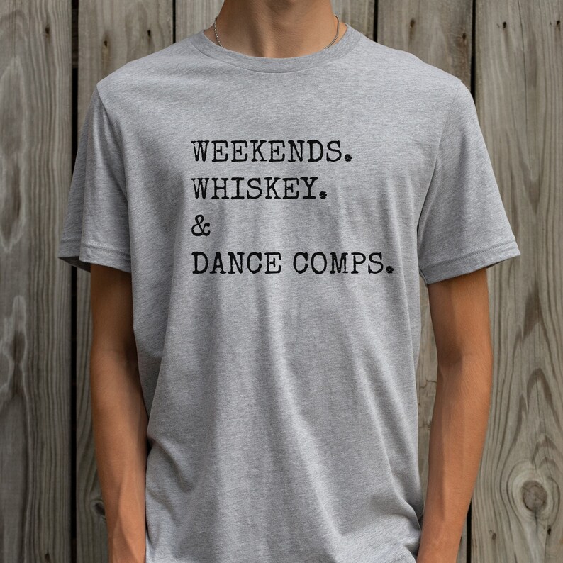 May include: A gray t-shirt with the text "Weekends. Whiskey. & Dance Comps." printed on the front.