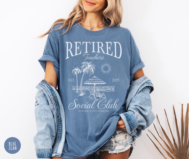 Puede incluir: Camiseta azul con el texto "RETIRED Teachers Social Club" y un gr&aacute;fico de playa. El gr&aacute;fico incluye palmeras, un sol, una sombrilla y el a&ntilde;o "2025". La camiseta es de estilo casual.