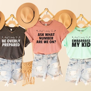 May include: Three t-shirts with different text on them. The text on the shirts reads "Most Likely To Be Overly Prepared", "Most Likely To Ask What Number Are We On?" and "Most Likely To Embarrass My Kid".