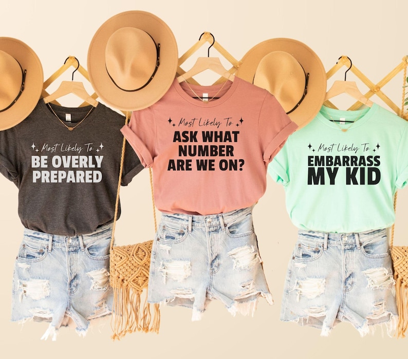 May include: Three t-shirts with different text on them. The text on the shirts reads "Most Likely To Be Overly Prepared", "Most Likely To Ask What Number Are We On?" and "Most Likely To Embarrass My Kid".
