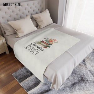May include: A white throw blanket with the text "Charlotte's Reading Blanket" and a stack of books with flowers on top. The blanket is 50x60 inches.