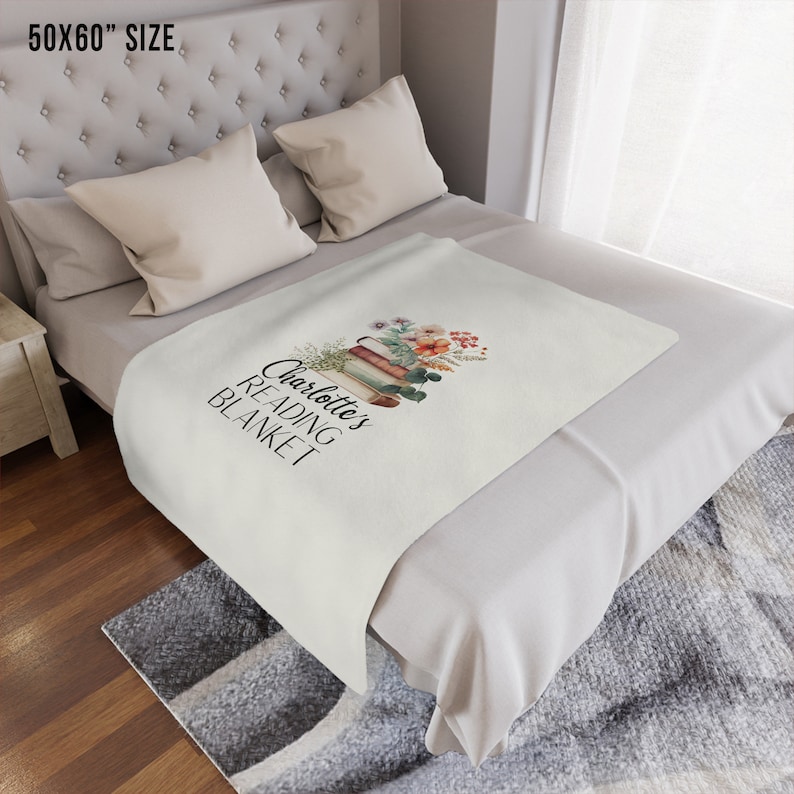 May include: A white throw blanket with the text "Charlotte's Reading Blanket" and a stack of books with flowers on top. The blanket is 50x60 inches.