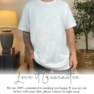 May include: A man wearing a light gray t-shirt with the text "Love it Guarantee" printed on the bottom. The text says "We are 100% committed to making you happy. If you are not in love with your shirt, please contact us right away. All items are made to order so we do not accepted returns but a replacement can be sent if there are any issues. Thank you for supporting our small, family run business. :)"