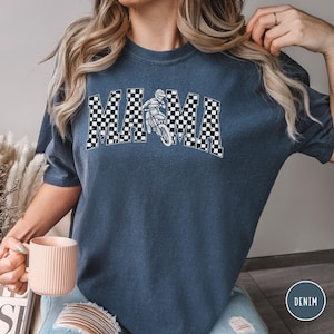 Peut inclure: Un t-shirt bleu marine avec un motif &agrave; carreaux blancs qui &eacute;pelle "MAMA" avec un graphique de pilote de motocross au centre.