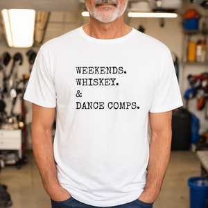 May include: White t-shirt with black text that reads "Weekends. Whiskey. & Dance Comps."