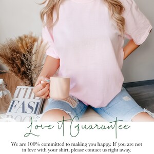 May include: A light pink short-sleeved t-shirt with a crew neckline, paired with light blue distressed denim shorts. The shirt is plain and solid-colored. The overall look is casual, featuring a simple design that focuses on the fabric and fit.