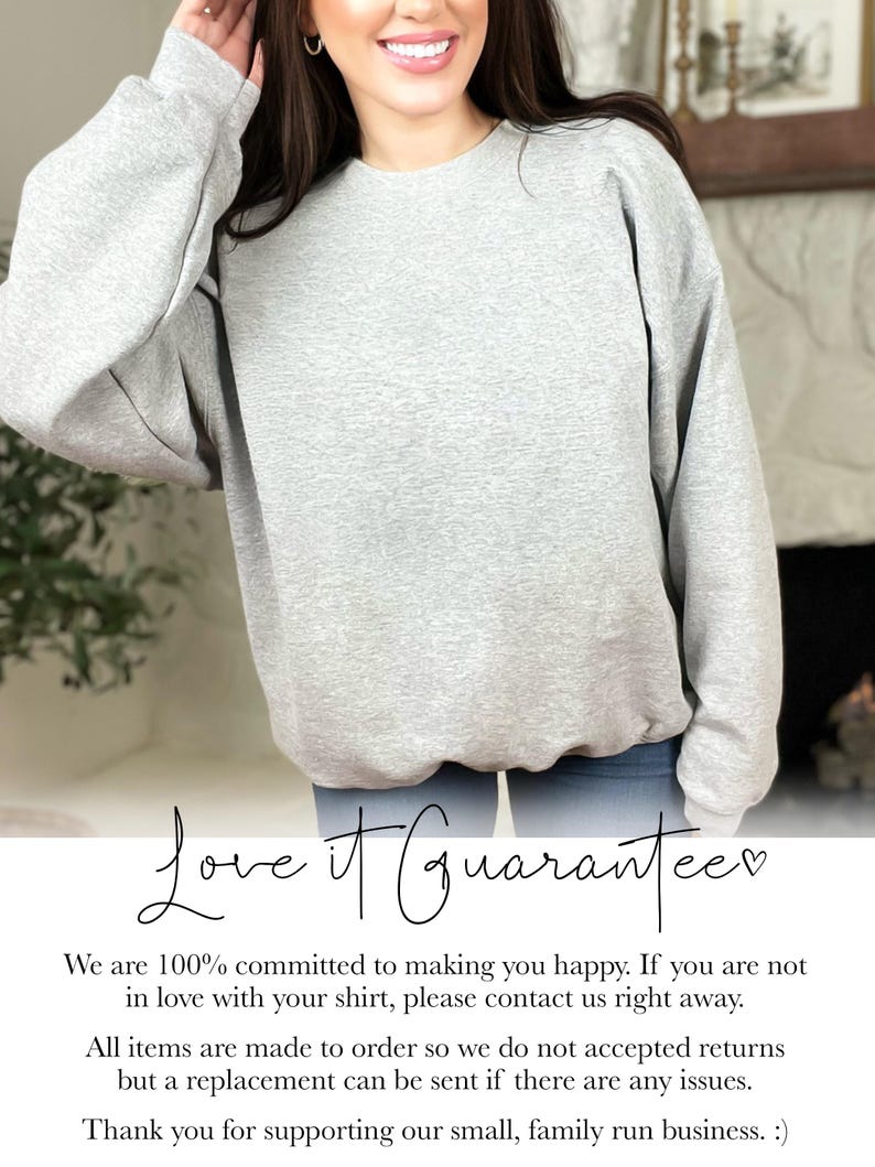 May include: A light gray sweatshirt with a crew neck. The text "Love it Guarantee" is written in cursive script. The sweatshirt is made of a soft material. The image is of a person wearing the sweatshirt.