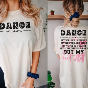 May include: An ivory t-shirt featuring the text DANCE mom on the front. The back displays DANCE mom followed by the text MY WALLET IS EMPTY, MY NERVES ARE SHOT, MY VOICE IS HOARSE, MY SCHEDULE IS CRAZY BUT MY heart is full with pink heart outlines.