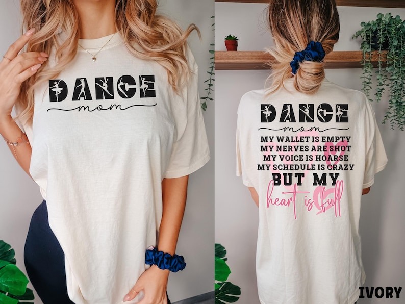 May include: An ivory t-shirt featuring the text DANCE mom on the front. The back displays DANCE mom followed by the text MY WALLET IS EMPTY, MY NERVES ARE SHOT, MY VOICE IS HOARSE, MY SCHEDULE IS CRAZY BUT MY heart is full with pink heart outlines.