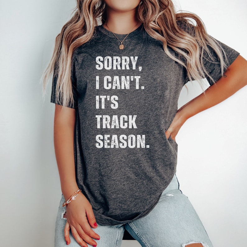May include: A dark grey t-shirt with the text "Sorry, I can't. It's track season." printed in white.