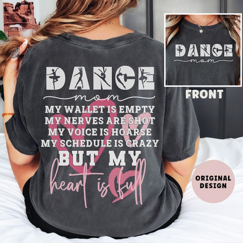 May include: A charcoal gray short-sleeve t-shirt featuring white and pink text and graphics. The back displays the word DANCE with silhouettes of dancers, followed by the text MY WALLET IS EMPTY, MY NERVES ARE SHOT, MY VOICE IS HOARSE, MY SCHEDULE IS CRAZY BUT MY heart is full. The front shows DANCE mom.