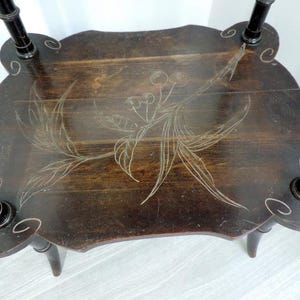 Puede incluir: Una mesa auxiliar de madera de color marr&oacute;n oscuro con una superficie rectangular de esquinas redondeadas y cuatro patas. La superficie est&aacute; decorada con un dibujo lineal grabado de color claro de una rama de cerezo con hojas y frutos.