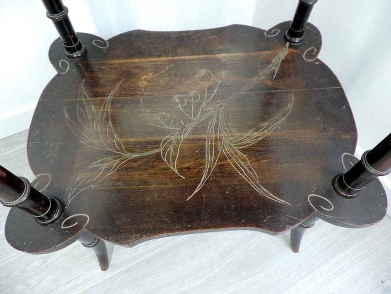 Puede incluir: Una mesa auxiliar de madera de color marr&oacute;n oscuro con una superficie rectangular de esquinas redondeadas y cuatro patas. La superficie est&aacute; decorada con un dibujo lineal grabado de color claro de una rama de cerezo con hojas y frutos.