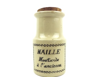 May include: A white ceramic jar with a cork lid and black lettering that reads "Maille Mustard à l'ancienne".