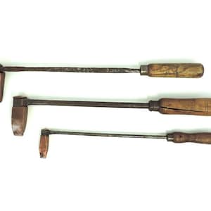 May include: Three antique soldering irons with wooden handles. The irons are different sizes and have a copper tip.