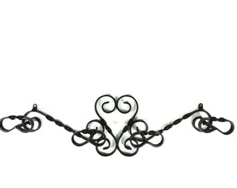 Op de afbeelding: Een zwarte metalen kapstok met een decoratief gerold ontwerp en vier haken.