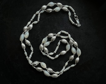 Långt, elegant, knutet halsband av silver, sötvattenspärlor och antika pärlemorpärlor.
