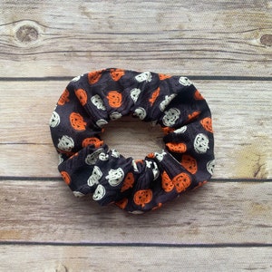 May include: A black scrunchie with a white and orange pumpkin pattern.