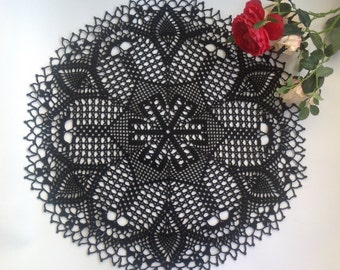 May include: A black crocheted doily with a delicate floral pattern. The doily is round and has a diameter of approximately 12 inches.