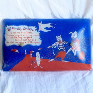 May include: A blue and red glass light fixture with a whimsical illustration of a cat, dog, cow, and a stick figure. The text reads "Hi diddle diddle. The cat and the fiddle. The cow jumped over the moon. The little dog laughed to see such fun and the dish ran away with the spoon."