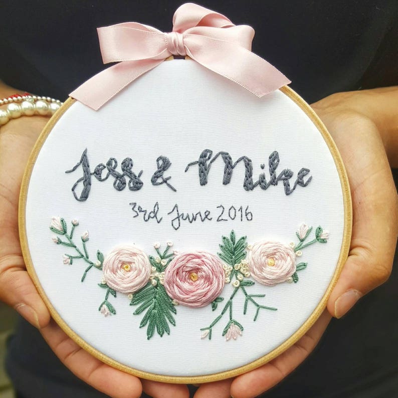 May include: Embroidered hoop with the names "Joss & Mike" and the date "3rd June 2016" in black thread. The hoop is decorated with pink and green floral embroidery.
