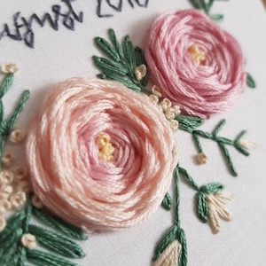 May include: Embroidered hoop art with pink flowers and green leaves. The text "August 2018" is stitched in black thread.