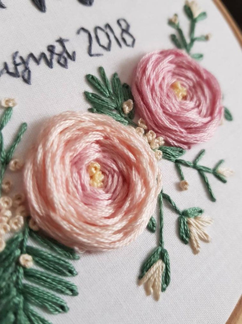 May include: Embroidered hoop art with pink flowers and green leaves. The text "August 2018" is stitched in black thread.