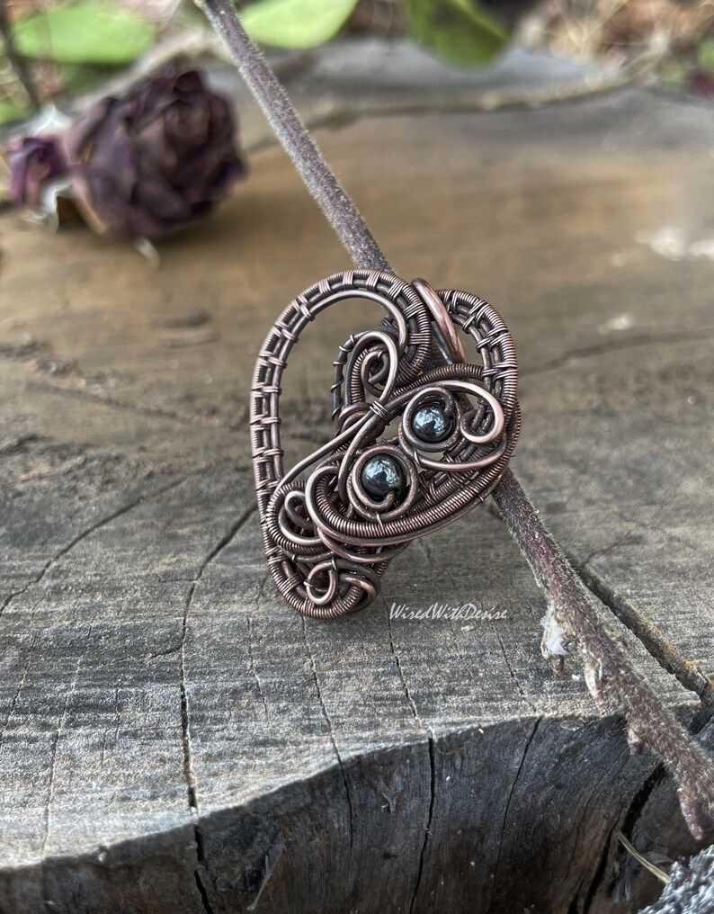 Heart-shaped antiqued and polished copper pendant with two small round Hematite beads.