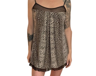 May include: A short, sleeveless, leopard print slip dress with a black lace trim. The dress has a black mesh panel at the neckline.