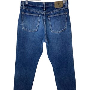 May include: A pair of blue denim jeans with a brown leather patch on the back pocket that says "Wrangler".