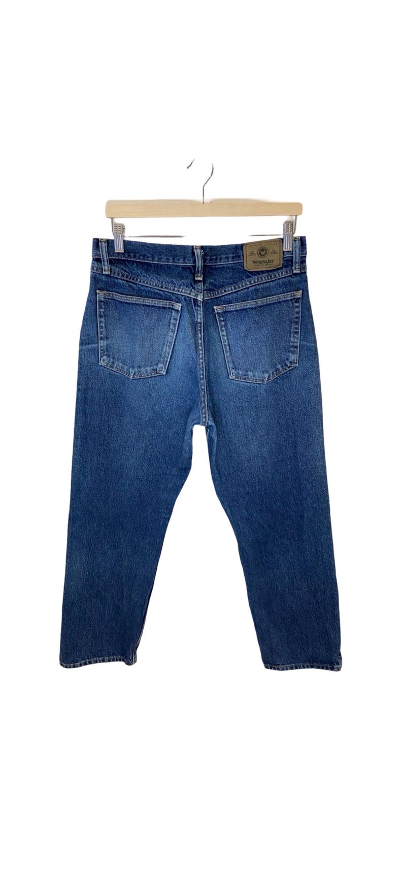May include: A pair of blue denim jeans with a brown leather patch on the back pocket that says "Wrangler".