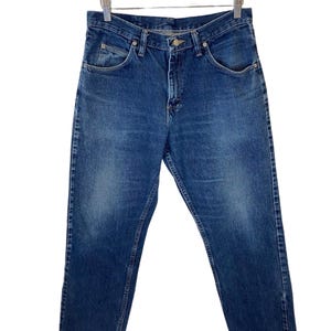May include: A pair of blue denim jeans with a button fly and five pockets.