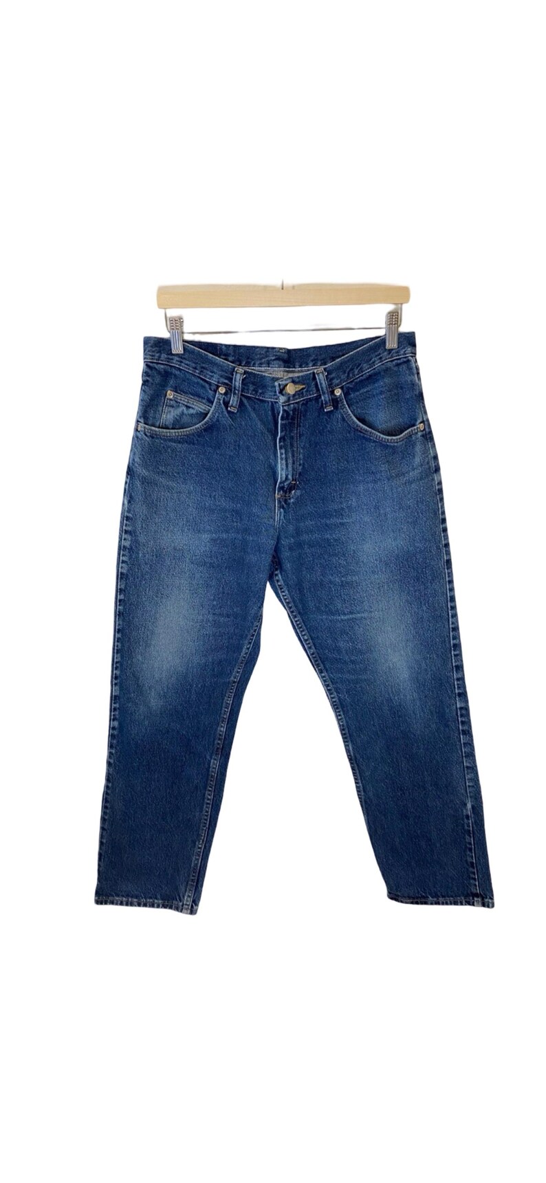 May include: A pair of blue denim jeans with a button fly and five pockets.