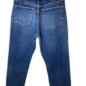 May include: A pair of blue denim jeans with a brown leather Wrangler label on the back pocket.