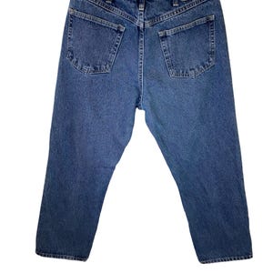 Pode incluir: Um par de cal&ccedil;as de ganga azul com um remendo de couro castanho que diz "Wrangler" no bolso de tr&aacute;s.