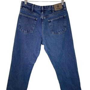 Pode incluir: Um par de cal&ccedil;as de ganga azul com um remendo de couro castanho que diz "Wrangler" nas costas.