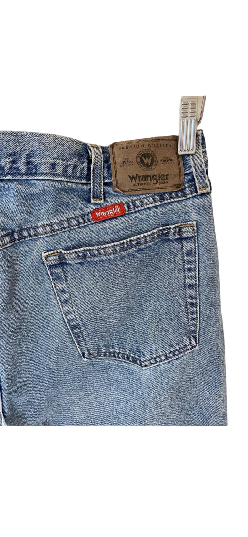 May include: A pair of light blue denim jeans with a brown leather patch that says "Wrangler Authentic Jeans" and a red patch that says "Wrangler".