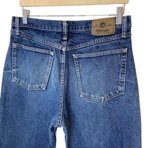 May include: A pair of blue denim jeans with a brown leather patch that says "Wrangler" on the back.