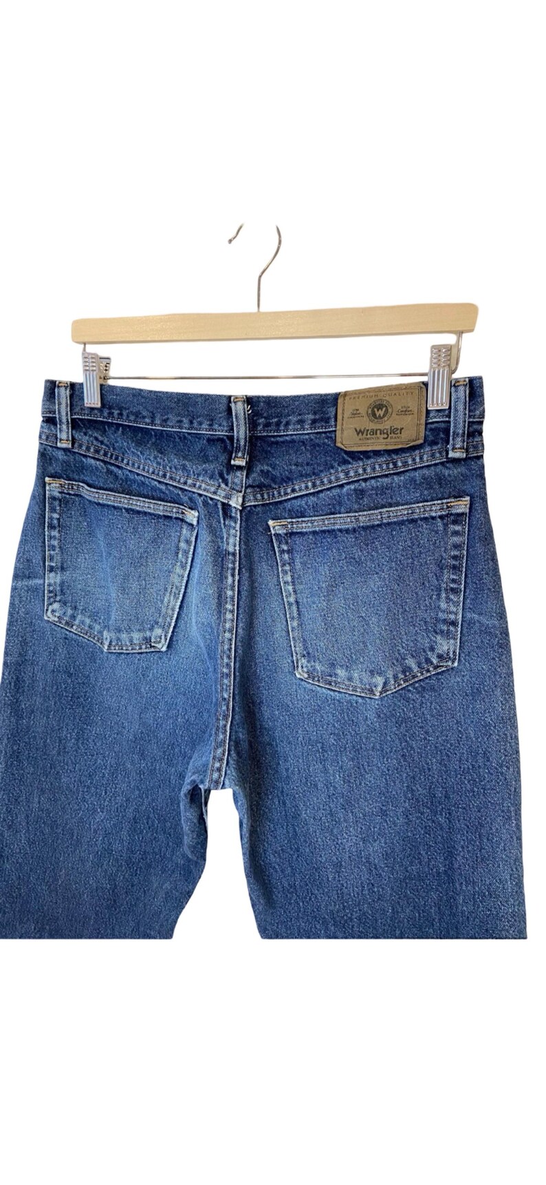 May include: A pair of blue denim jeans with a brown leather patch that says "Wrangler" on the back.