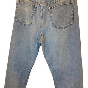 Peut inclure: Un jean en denim bleu clair avec une &eacute;tiquette Wrangler en cuir marron sur la poche arri&egrave;re.