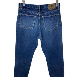 May include: A pair of blue denim jeans with a brown leather patch on the back pocket that says "Wrangler".