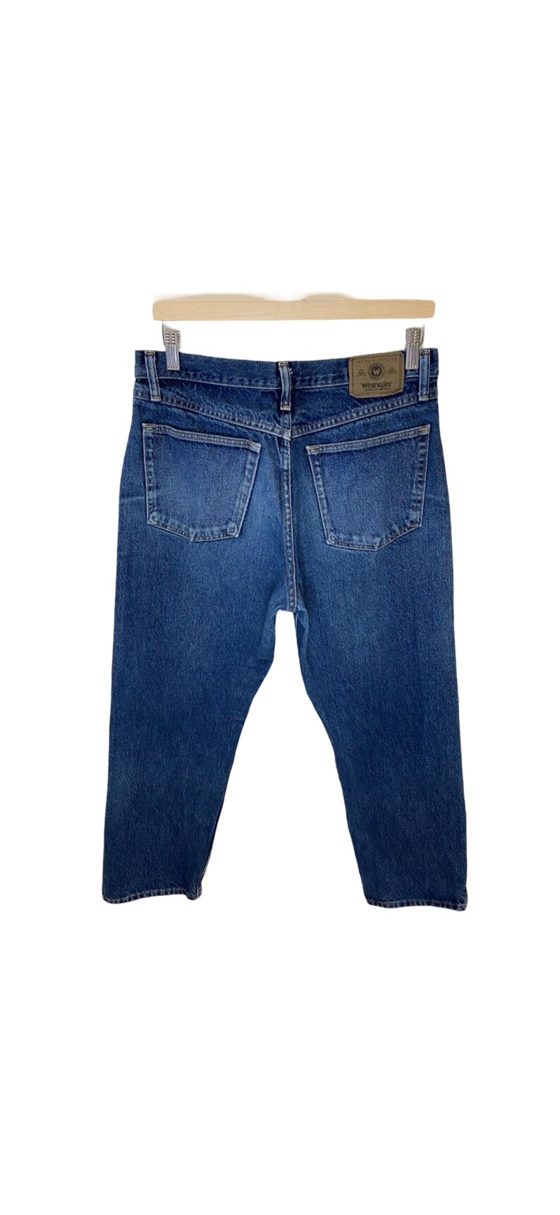 May include: A pair of blue denim jeans with a brown leather patch on the back pocket that says "Wrangler".
