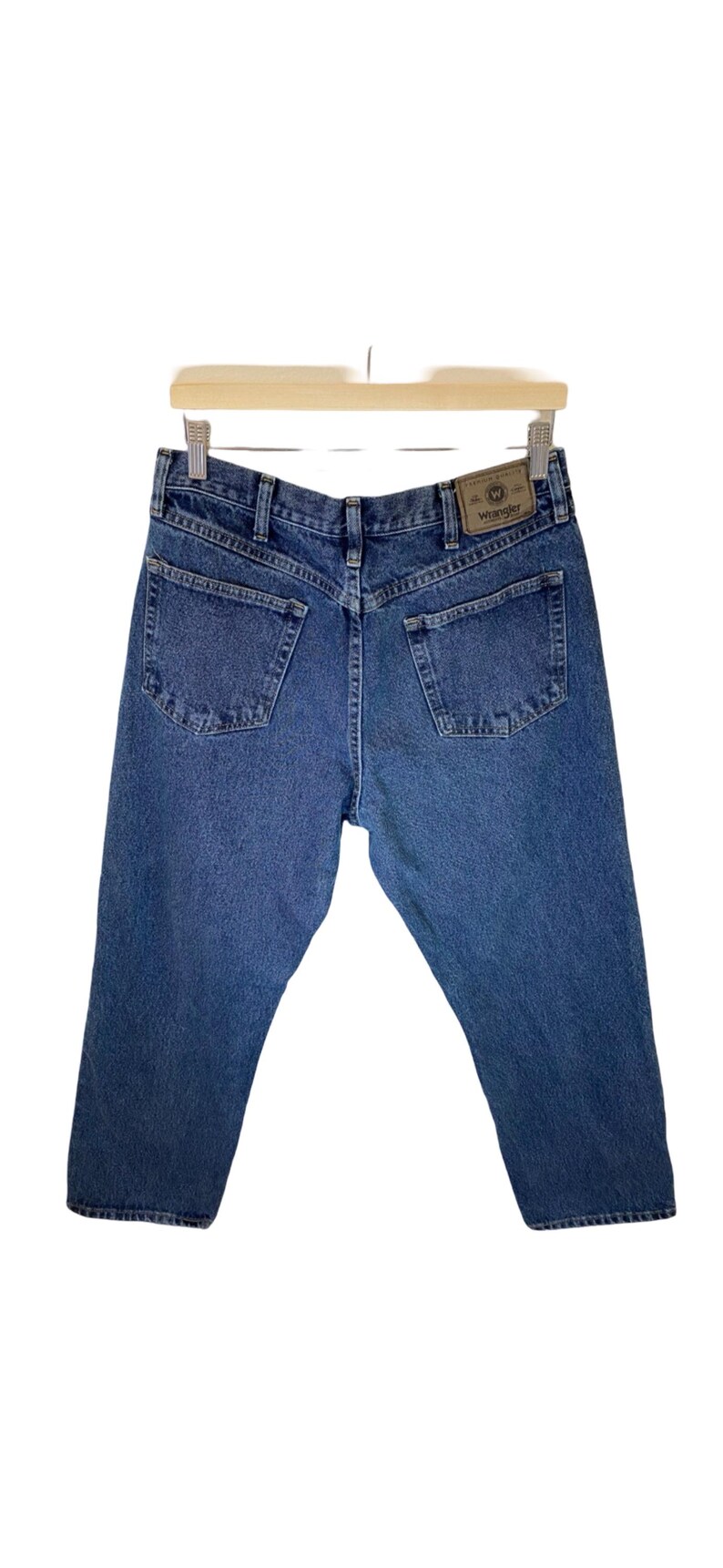 Pode incluir: Um par de cal&ccedil;as de ganga azuis com uma etiqueta Wrangler de couro castanho no bolso de tr&aacute;s.
