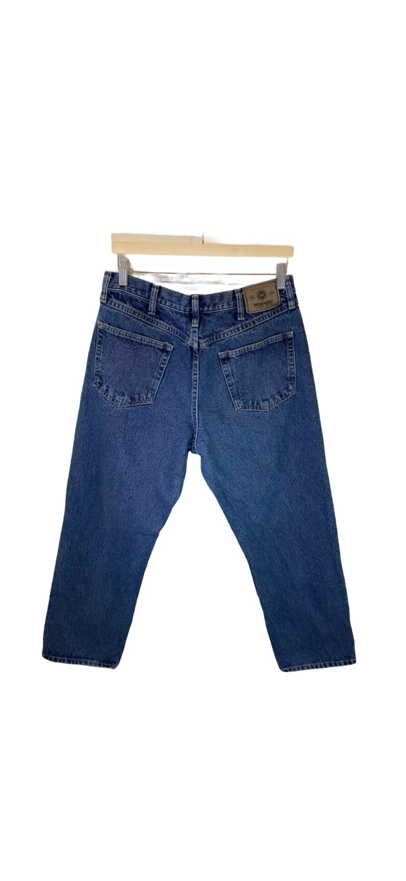 Pode incluir: Um par de cal&ccedil;as de ganga azuis com um remendo de couro castanho no bolso de tr&aacute;s que diz "Wrangler".